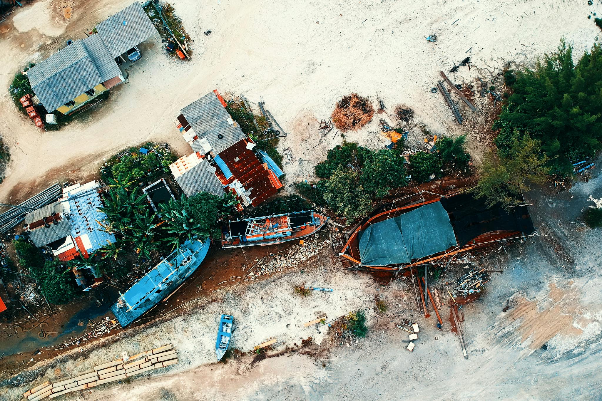 Aerial photo of a boat repair yard with various vessels and lush greenery.